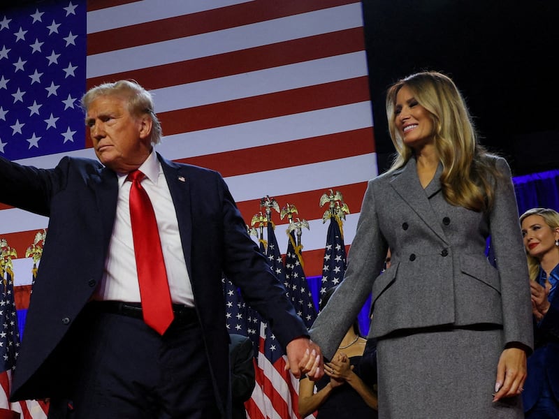 Donald Trump (left) holds hands with Melania Trump (right).