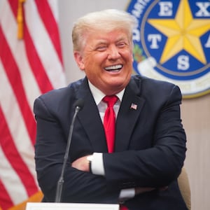 Donald Trump laughs behind a lectern.