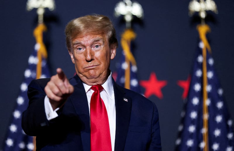 Donald Trump makes a face while pointing forward on stage at a campaign event.