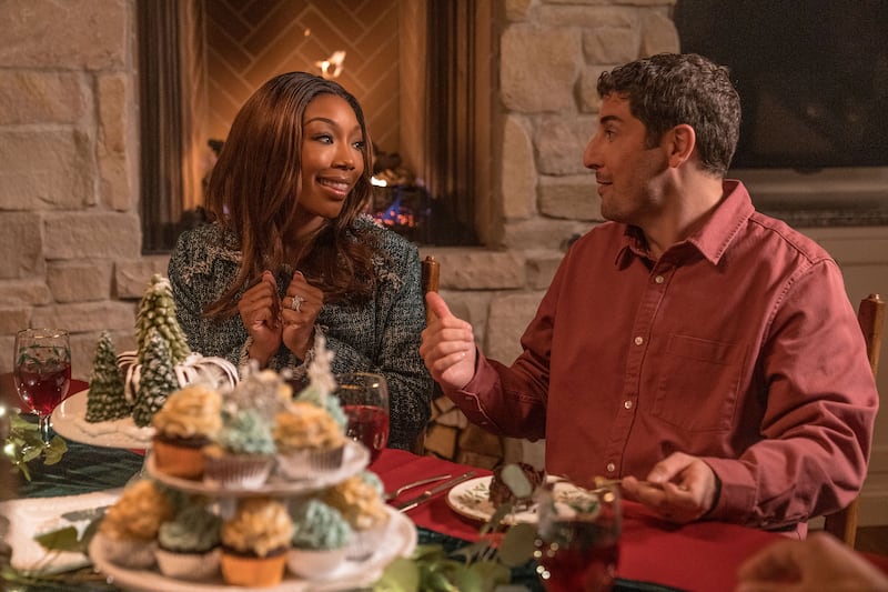 Brandy Norwood and Jason Biggs sit next to each other at a dinner table in a still from ‘Best Christmas Ever’