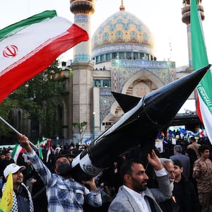 A photo including Iranians carrying a model of a missile 