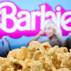 A popcorn and Barbie movie website displayed on a screen in the background