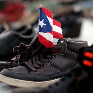 shoes holding puerto rico flag death toll maria katrina counting death statistic demography george washington harvard university climate change global warming