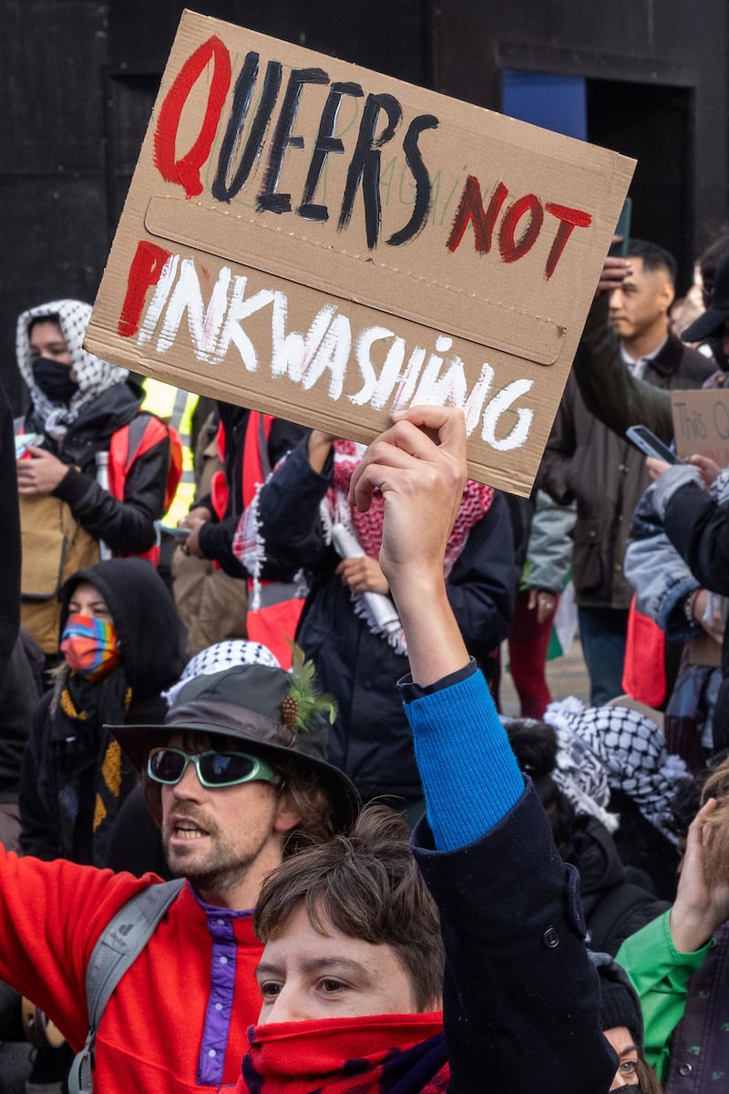 A LGBT+ pro-Palestinian protester from the Free Palestine Coalition holds up a sign criticising Israeli 'pinkwashing' during a march through central London.