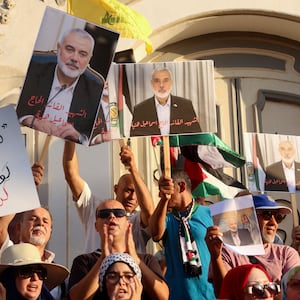 Demonstrators carry pictures of Hamas leader Ismail Haniyeh