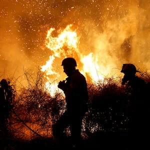 Firefighters work to put out a fire in an open field, following a mass-infiltration by Hamas gunmen from the Gaza Strip