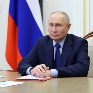 Russian President Vladimir Putin sits in char before Russian flag