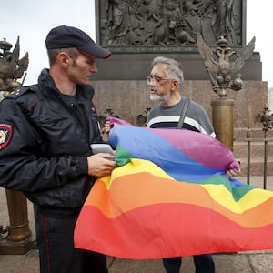 Policemen talk to a gay rights activist holding a rainbow flag during a protest in Dvortsovaya Square in St. Petersburg, Russia, Aug. 2, 2015. 