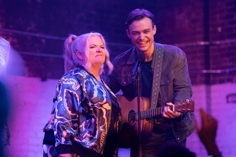 A photo still of Paula Pell as Gloria and Thomas Doherty in Girls5eva