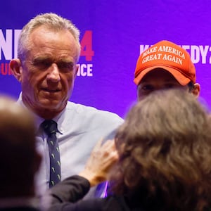 A photo of RFK Jr. with his arm around a person wearing a MAGA hat.