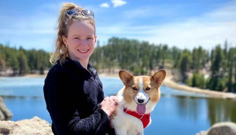 Betty Bowman smiles with a dog with a lake in the background.