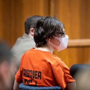 Ethan Crumbley, wearing a mask and an orange prison jumpsuit, stares forward in court.