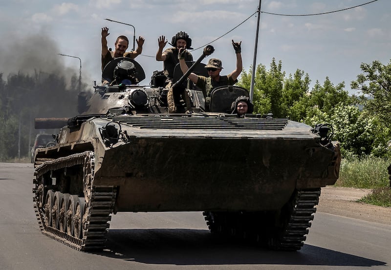 Ukraine soldiers ride on top of an armored vehicle during the war against Russia.