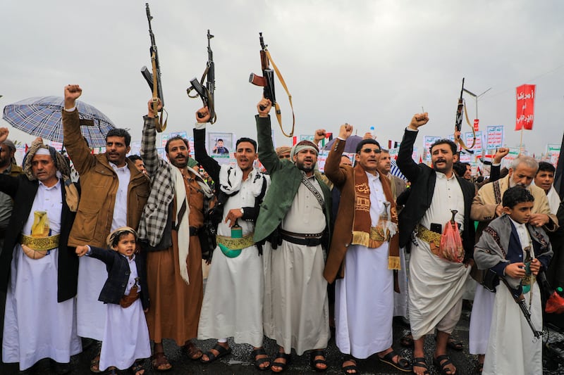 People lift rifles and placards as they chant during an anti-Israel and anti-US rally in the Huthi-controlled capital Sanaa on January 19, 2024, 