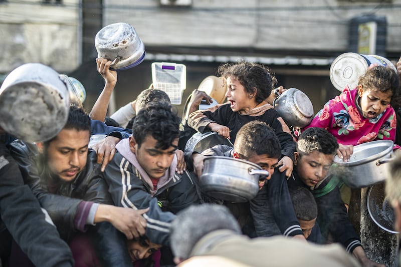 Palestinians in Rafah line up to receive food distributed by aid organizations.