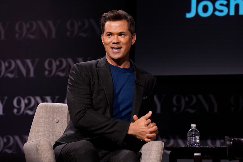 Andrew Rannells sits on a chair.