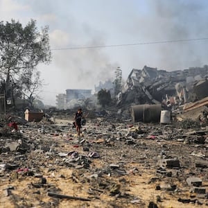 A photograph of a Palestinian boy walking by the buildings destroyed in the Israeli bombardment on al-Zahra, on the outskirts of Gaza City on October 20, 2023.