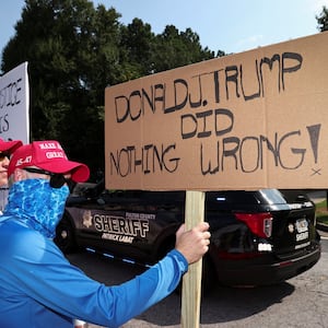 A supporter of former President Donald Trump holds a banner at the entrance of the Fulton County Jail, as Trump is expected to turn himself in to be processed after his Georgia indictment, in Atlanta, Georgia.