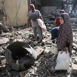 A photo including Palestinians searching for their belongings among the rubble in Gaza City