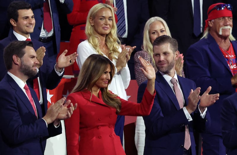 Melania Trump waving surrounded by other Trump