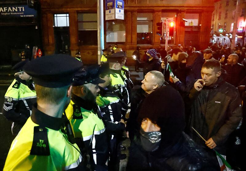 People stand in front of riot police near the scene of a suspected stabbing that left few children injured in Dublin, Ireland, November 23, 2023.