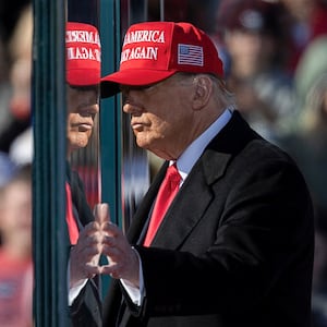 Republican presidential nominee and former U.S. President Donald Trump touches the protective glass, during a campaign rally, in Lititz, Pennsylvania, U.S. November 3, 2024.