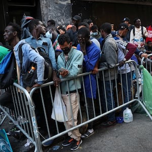 Recently arrived migrants to New York City wait on the sidewalk outside of the Roosevelt Hotel