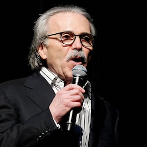 David Pecker holds a microphone while speaking on stage.