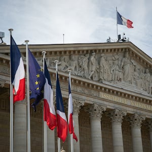 French flags are seen by a side of the facade of the National Assembly