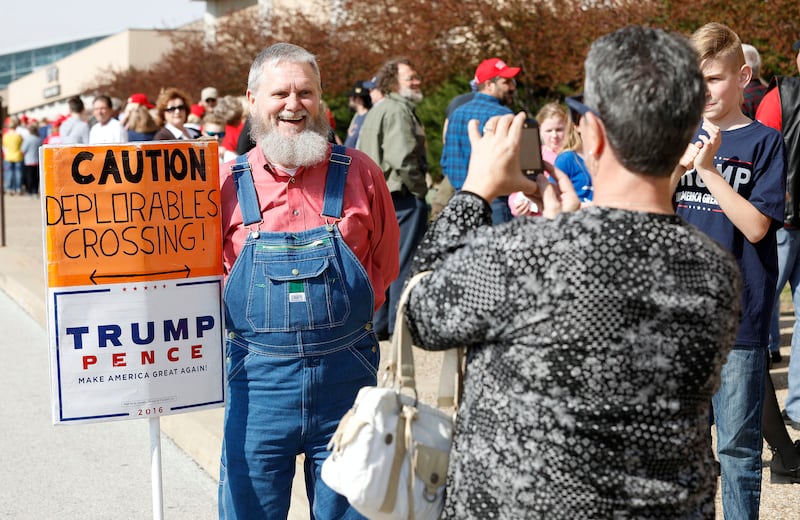 A Trump supporter poses for a picture with a "Caution Deplorables Crossing!" at a Trump rally in 2017.