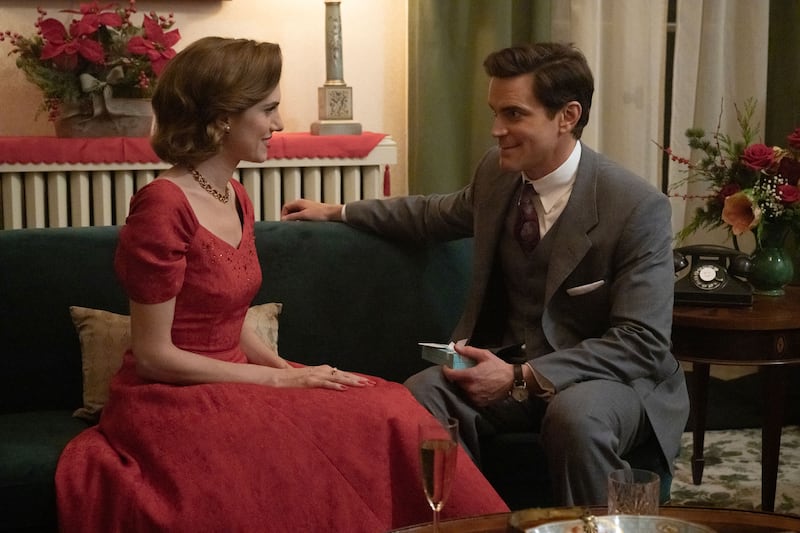 Allison Williams and Matt Bomer sit on a couch in a still from ‘Fellow Travelers’